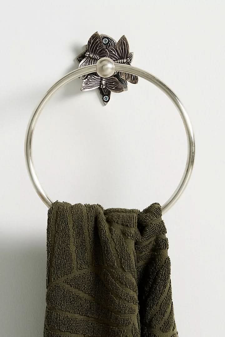 Silver butterfly-design wall-mounted bathroom accessories set holds a dark green towel.
